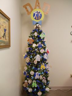 a decorated christmas tree in the corner of a room with a dad's day sign on it