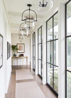 a long hallway with lots of windows and chandeliers hanging from the ceiling above it