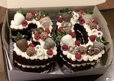 two chocolate cakes in a box with strawberries and cream toppings on the top