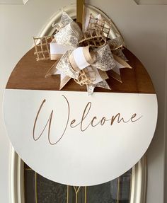 a welcome sign hanging on the front door of a house with ribbons and bows attached to it