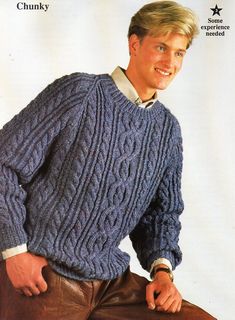 a man in a blue cabled sweater poses for a magazine cover with his hands on his hips