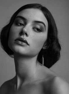 a black and white photo of a woman's face with earrings on her head