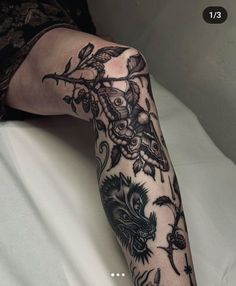 a woman's arm with tattoos on it and an owl in the middle, sitting on a bed