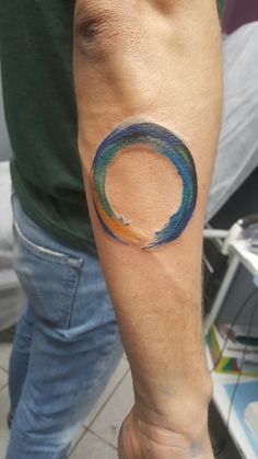 a man with a tattoo on his arm has a blue and orange wave in the center