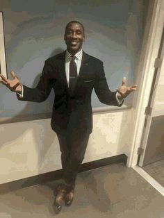 a man wearing a suit and tie standing in front of a mirror with his hands out