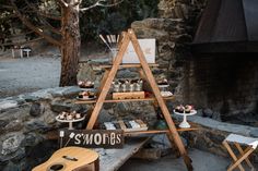 a wooden table topped with desserts next to a fire place filled with rocks and trees