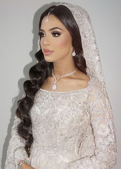 a woman in a wedding dress with long hair wearing a bridal veil and diamond jewelry