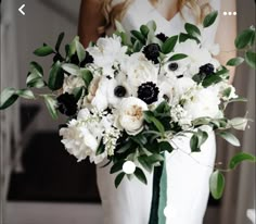 a bride holding a bouquet of white and black flowers