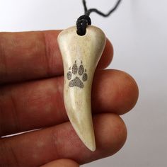 a hand holding a small bone with a paw print on it