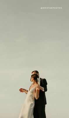 a bride and groom are standing on the beach