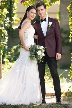 a bride and groom posing for a photo under an arch with greenery in the background