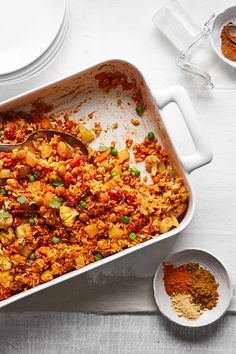 a casserole dish filled with rice, vegetables and seasoning on a table