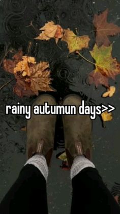 someone is standing in the rain with their feet up and autumn leaves on the ground