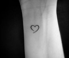 a small heart tattoo on the wrist is shown in black and white, with an arrow