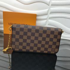 a brown and black checkered purse sitting on top of a table next to a box