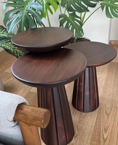 three wooden tables sitting on top of each other in front of a potted plant