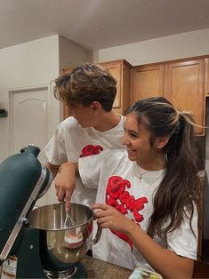 two young people are making something in the kitchen