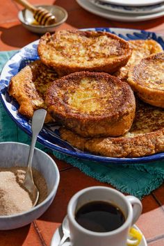 some french toast on a blue and white plate with two cups of coffee next to it