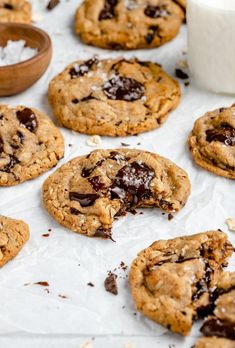 chocolate chip cookies and marshmallows sit on wax paper next to a glass of milk