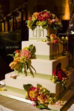 a three tiered wedding cake with flowers on the top and bottom, sitting on a table