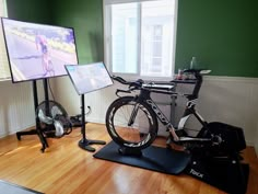 there is a bike that is sitting on the floor in front of a flat screen tv