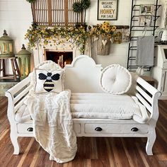 a white day bed with pillows and blankets on it in front of a fire place