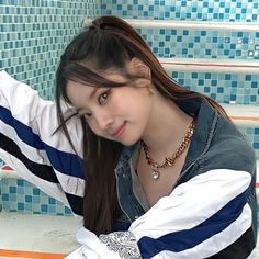 a young woman sitting on the ground in front of some blue tiled walls and stairs