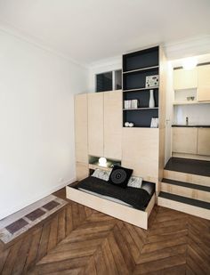 a bed sitting on top of a wooden floor next to a book shelf filled with books