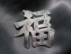 "This Chinese silver brooch is in the shape of the symbol for happiness, according to a number of online sources, and I think that's more than appropriate.  The floral engraving, with finely textured background, covers the pin's front.  I think the plant is bamboo, and when I looked up the symbolism of bamboo in Chinese culture, I started laughing, as every site I found gave a different quality attached to it -- virtue, strength, loyalty, integrity, good luck . . .  The maker's mark on the back Traditional Engraved Brooches For Gift, Spiritual Silver Brooch For Gift, Traditional Silver Brooches For Anniversary, Silver Engraved Brooch For Anniversary, Symbol For Happiness, Happiness Symbol, Floral Engraving, Chinese Export, Digital Scale