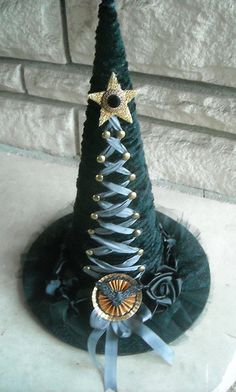 a small christmas tree hat on top of a black hat with gold stars and ribbons