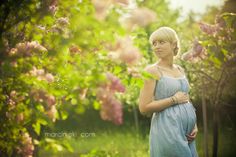 a pregnant woman standing in front of flowers