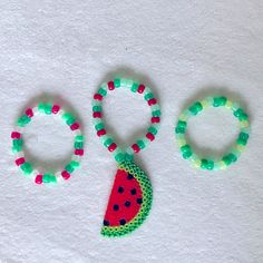 two bracelets and a watermelon shaped brooch on a white surface with the word oo spelled out