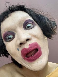 a woman with black hair and makeup has her face painted like a clown's head