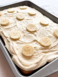 a pan filled with white frosting and banana slices