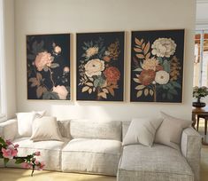 three floral paintings hang on the wall above a white couch in a room with hardwood floors