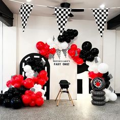 black and white balloons are on display in front of an arch with checkered flags