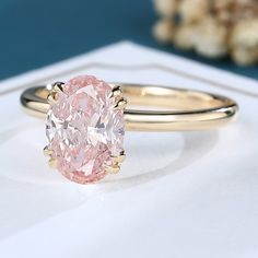 a pink diamond ring sitting on top of a table