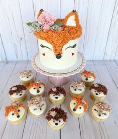 cupcakes are arranged in front of a cake with an animal face on it