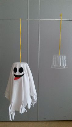 two white towels hanging from hooks in front of a gray wall with yellow handles and one has a ghost face on it