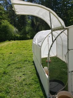 an outdoor chicken coop in the middle of a grassy field with a white cover over it