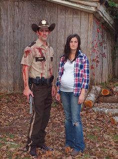 a man and woman dressed in costumes standing next to each other on the ground with leaves all over them