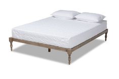 the bed is made with white linens and wooden legs on each side, along with two pillows