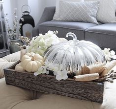 a glass pumpkin sitting on top of a wooden tray filled with flowers and other decorations