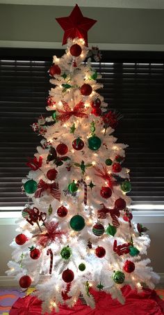 a white christmas tree with red and green ornaments