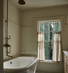 an old fashioned bathtub sits in front of a window