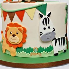 a birthday cake with an animal, zebra and lion decoration on the top is decorated in fondant