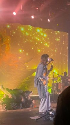 a man standing on top of a stage next to a woman holding a guitar in front of him