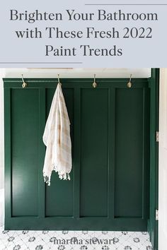 a bathroom with green cabinets and white towels hanging from hooks on the wall above it