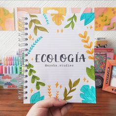 a hand holding up a notebook with the word ecologia written in front of it