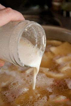 someone pouring milk into a pot of food